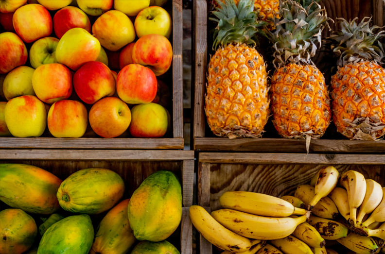 variedade de frutas tropicais, incluindo uvas, peras, figos e frutas exóticas, dispostas em uma composição rica em tons de verde, vermelho, amarelo e laranja. A imagem destaca texturas e formas únicas, evocando frescor e diversidade.