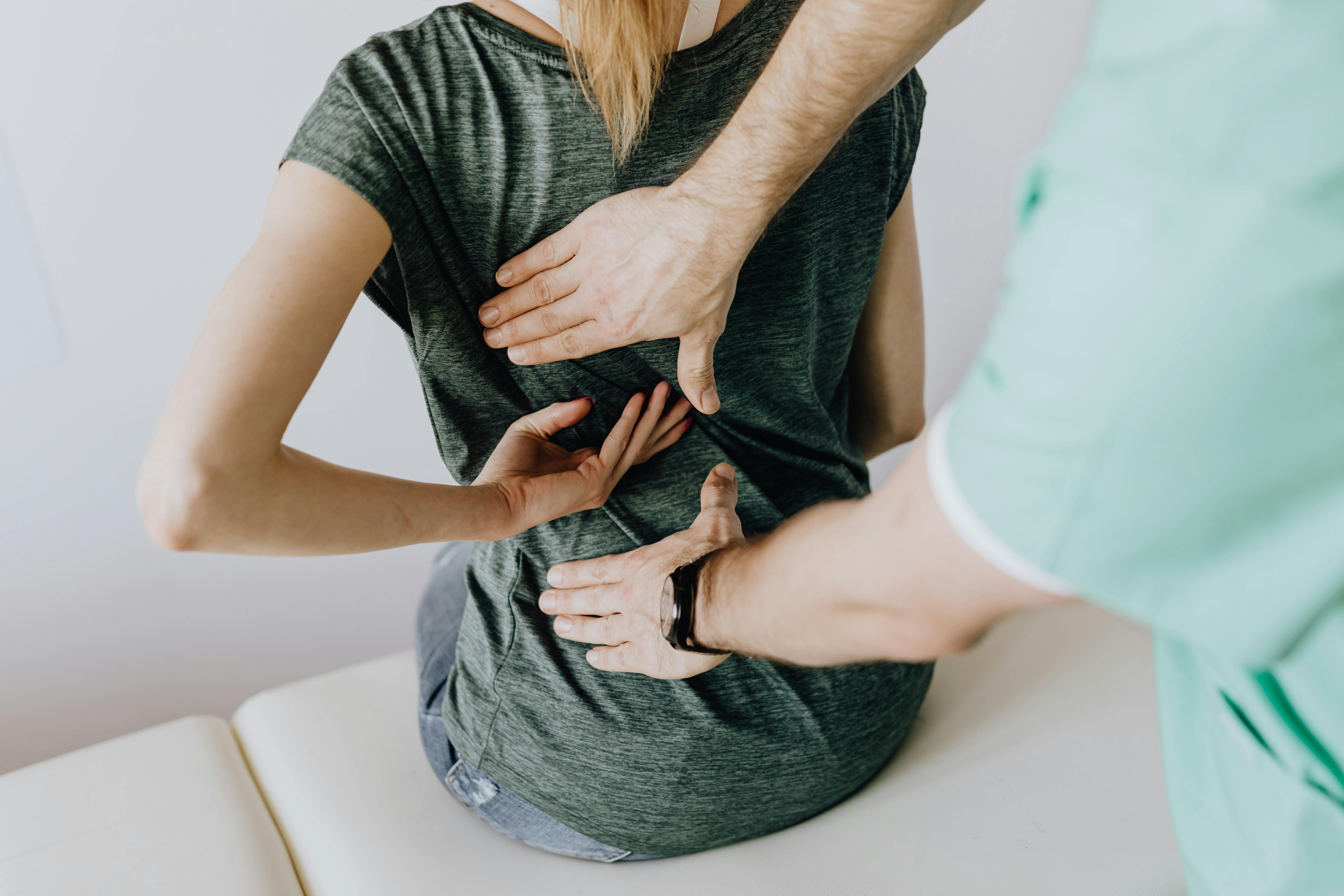 Fisioterapeuta realizando avaliação e tratamento em paciente com dor nas costas, destacando a importância da reabilitação e cuidados com a saúde postural.